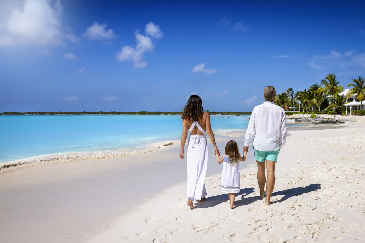 A family walking together on a bright, turquoise Bahamian beach.